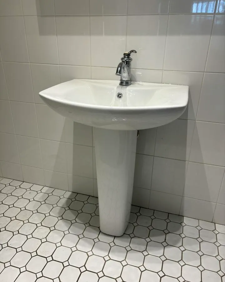 Pedestal basin with a chrome tap on a tiled floor